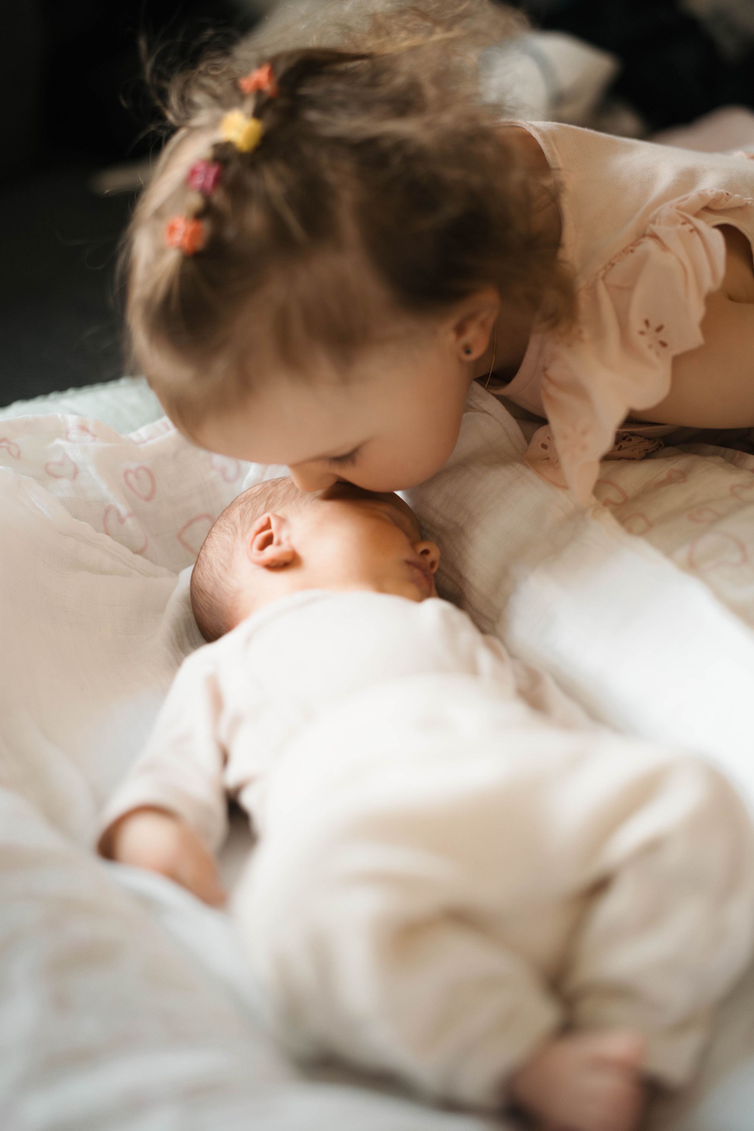 Baby newborn sister kissing face