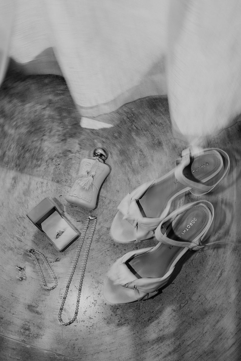 Flatlay of bridal details with shoes, fragrance, and jewelry captured at Blue Venado Sea Side.