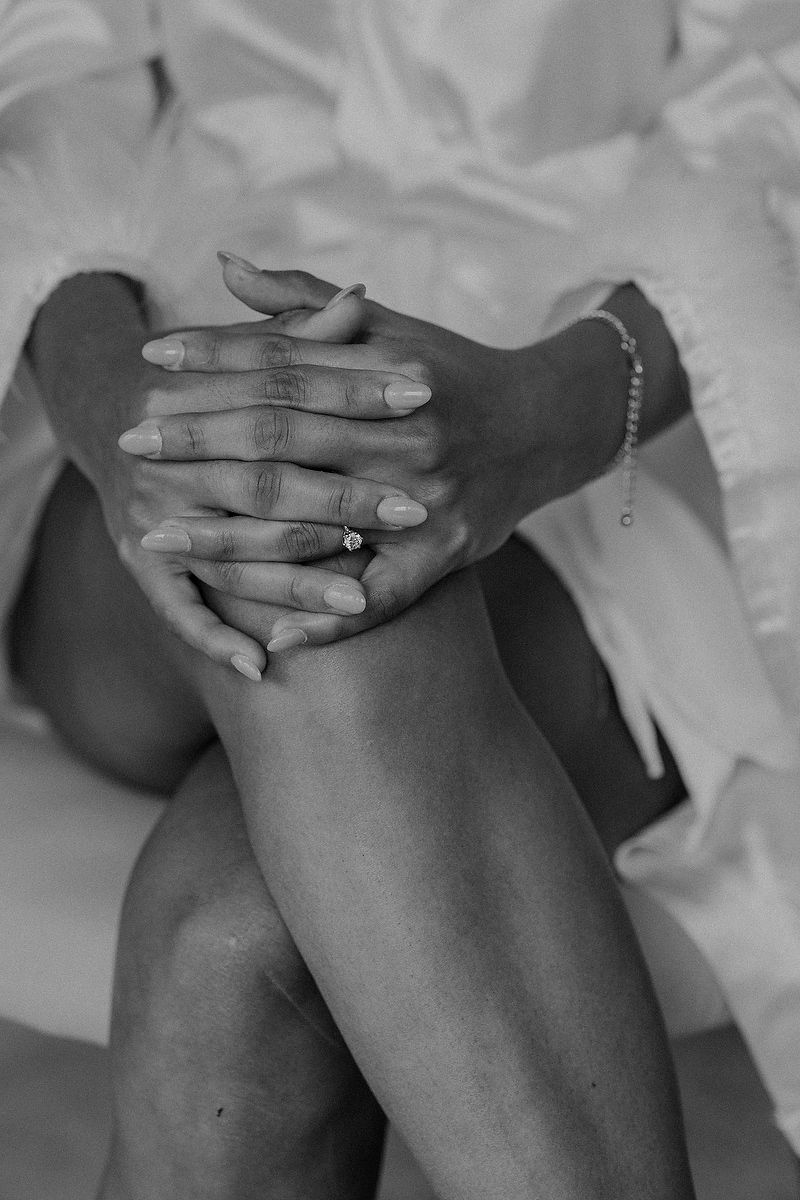 Black and white close-up photos of hands with rings resting on knees in a wedding dress.