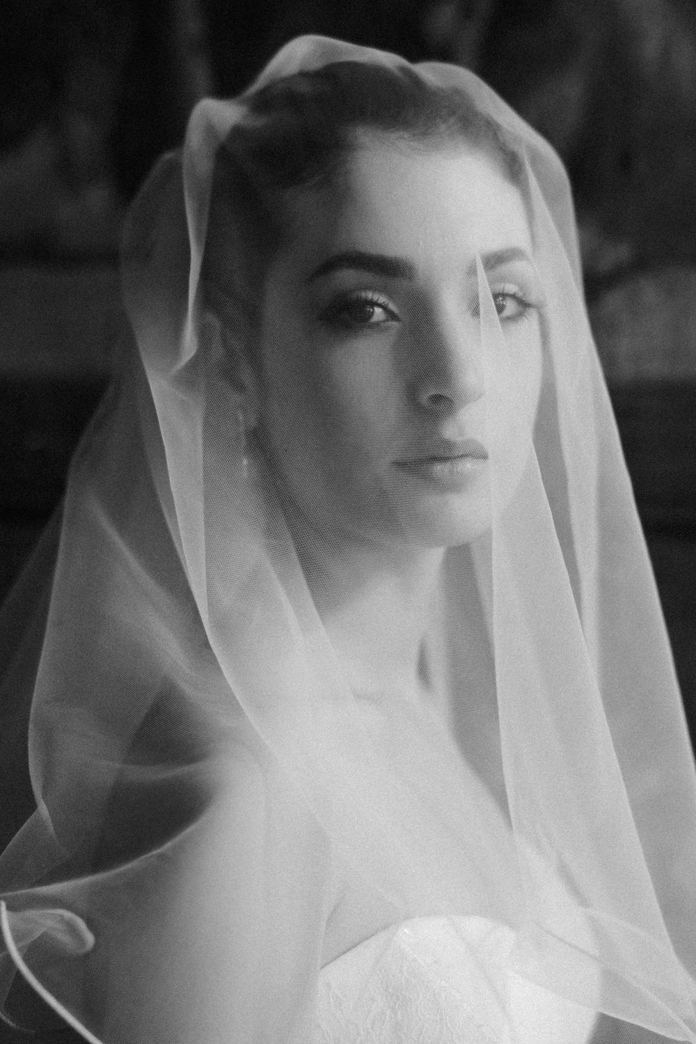 A sequence of five black and white portraits showing a bride wearing a delicate veil in different ethereal poses.