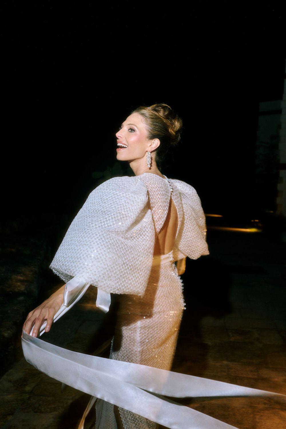 A dancer in a white dress performs an expressive spinning movement sequence on a dark stage.
