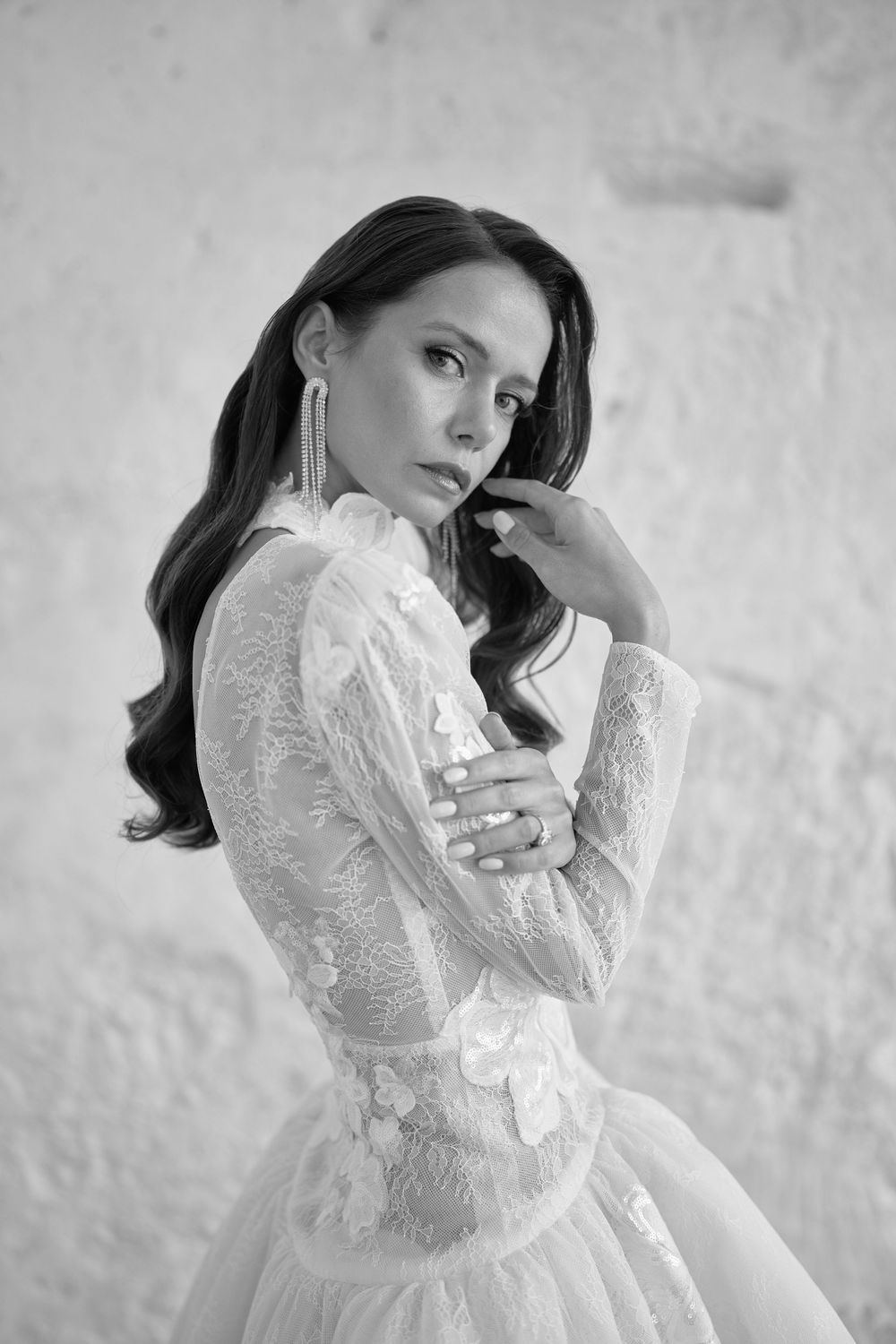 Black and white portrait of someone in an elegant lace wedding dress with long sleeves and flowing details. Wedding photographer Puglia