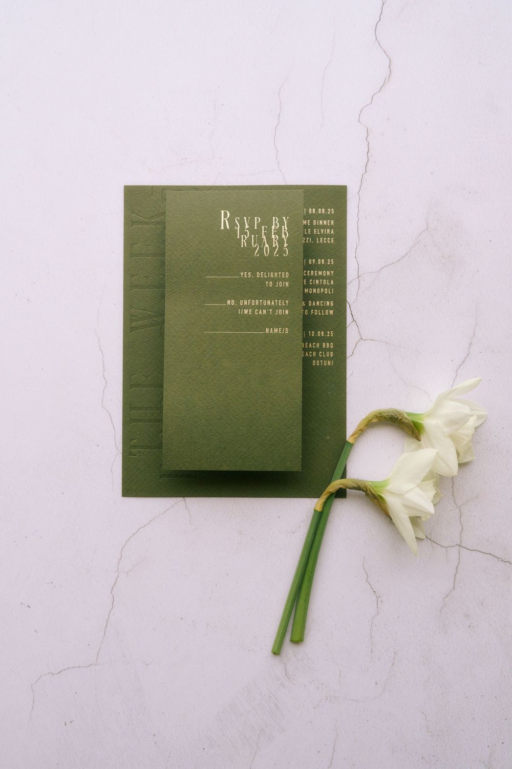 Minimalist green business cards arranged with white daffodils on a light marble surface.