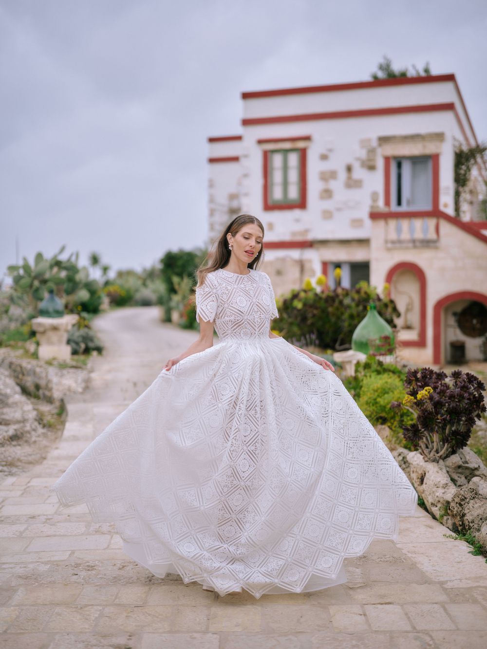 A stunning white lace wedding dress twirls gracefully against a rustic Mediterranean villa backdrop. Wedding photographer in Puglia