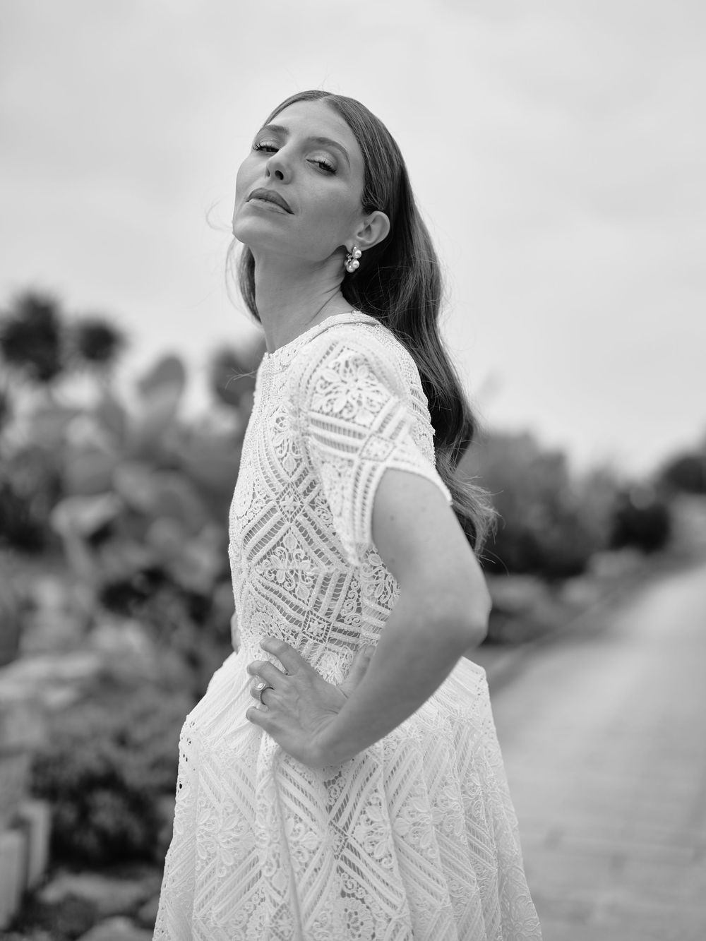 Black and white portrait series showing a person in a white lace dress posing expressively against a blurred background.