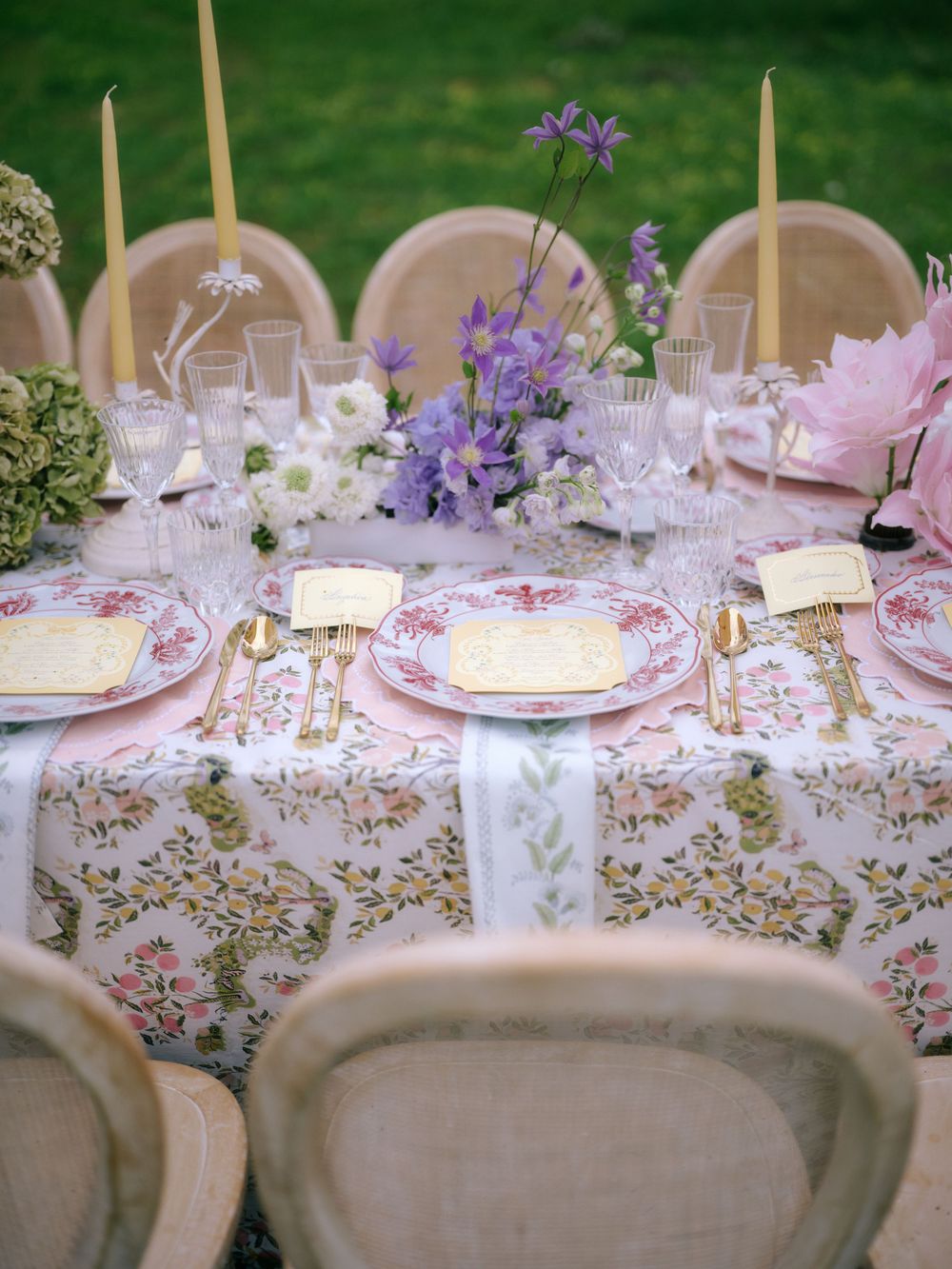 Elegant wedding reception table setting with floral tablecloth, purple flowers, and pink accents. Puglia wedding photographer