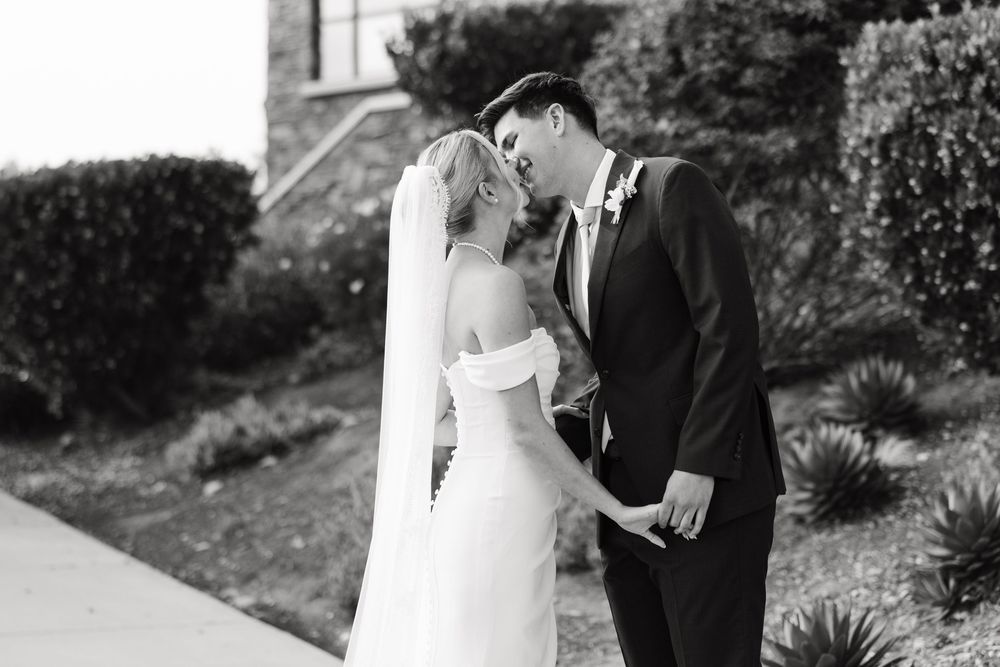 A couple embraces during their wedding photoshoot in an outdoor garden setting with natural lighting.