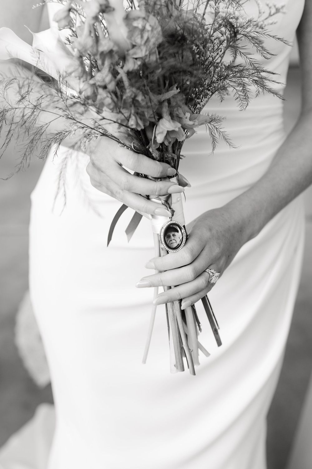 Close-up view of delicate wedding bouquet held against white bridal gown.