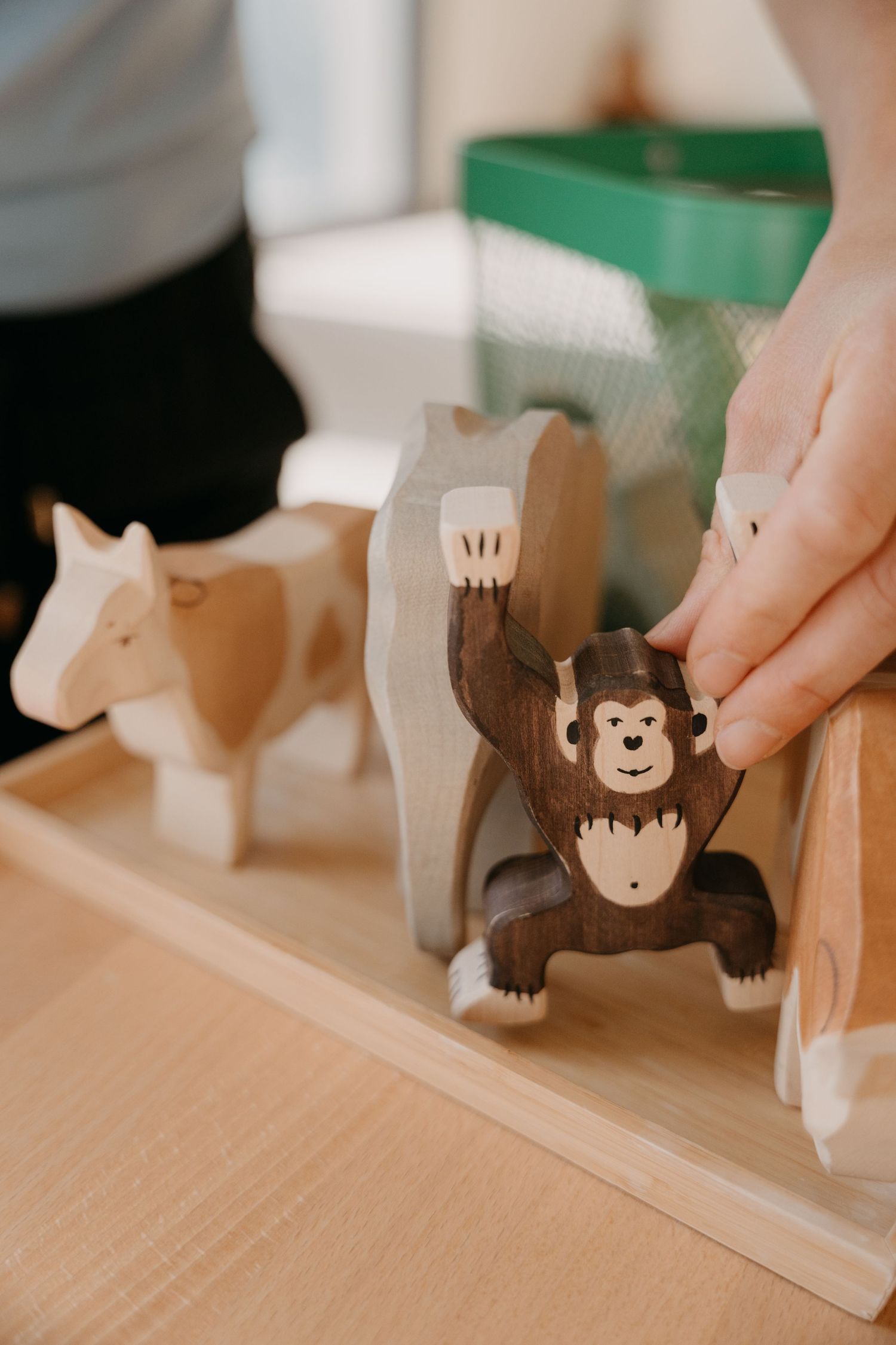 Wooden toy monkey figures arranged in a row showing progressive painting stages on natural wood surface.