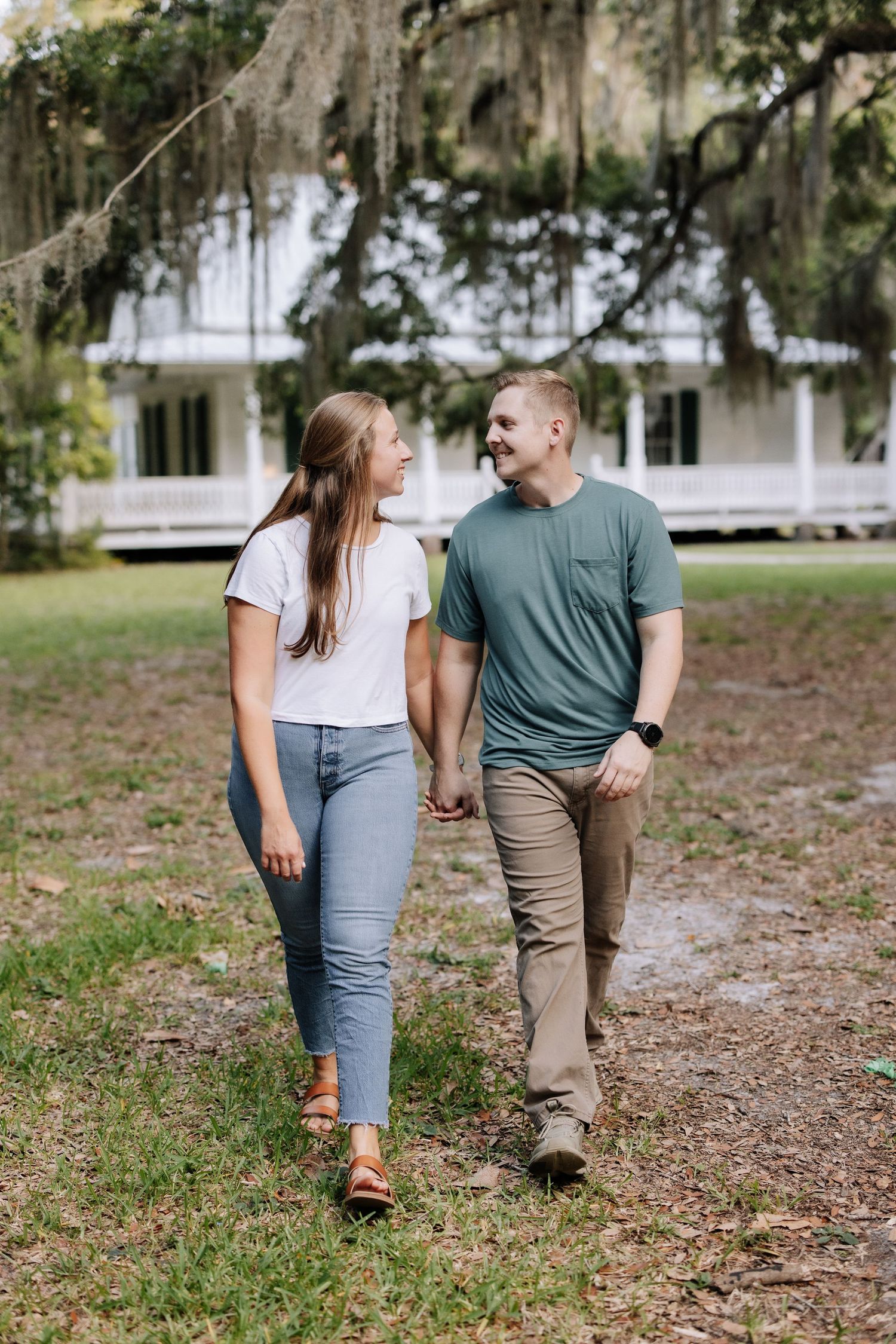 A couple shares a romantic moment sitting in a sun-drenched field at golden hour while dressed in casual summer attire.