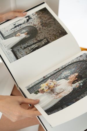 Hands arranging a series of black and white photographic prints laid out on a white surface.