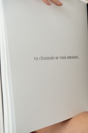 Open pages of a minimalist white book showing faint text against blank space.