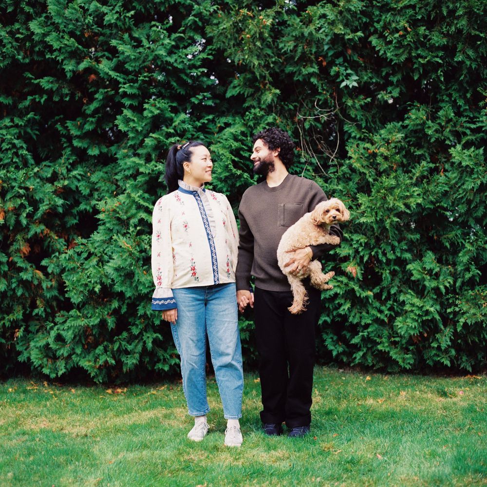 120mm color photograph of couple looking at each other while their dog looks directly at the camera during a maternity photoshoot in Maine.