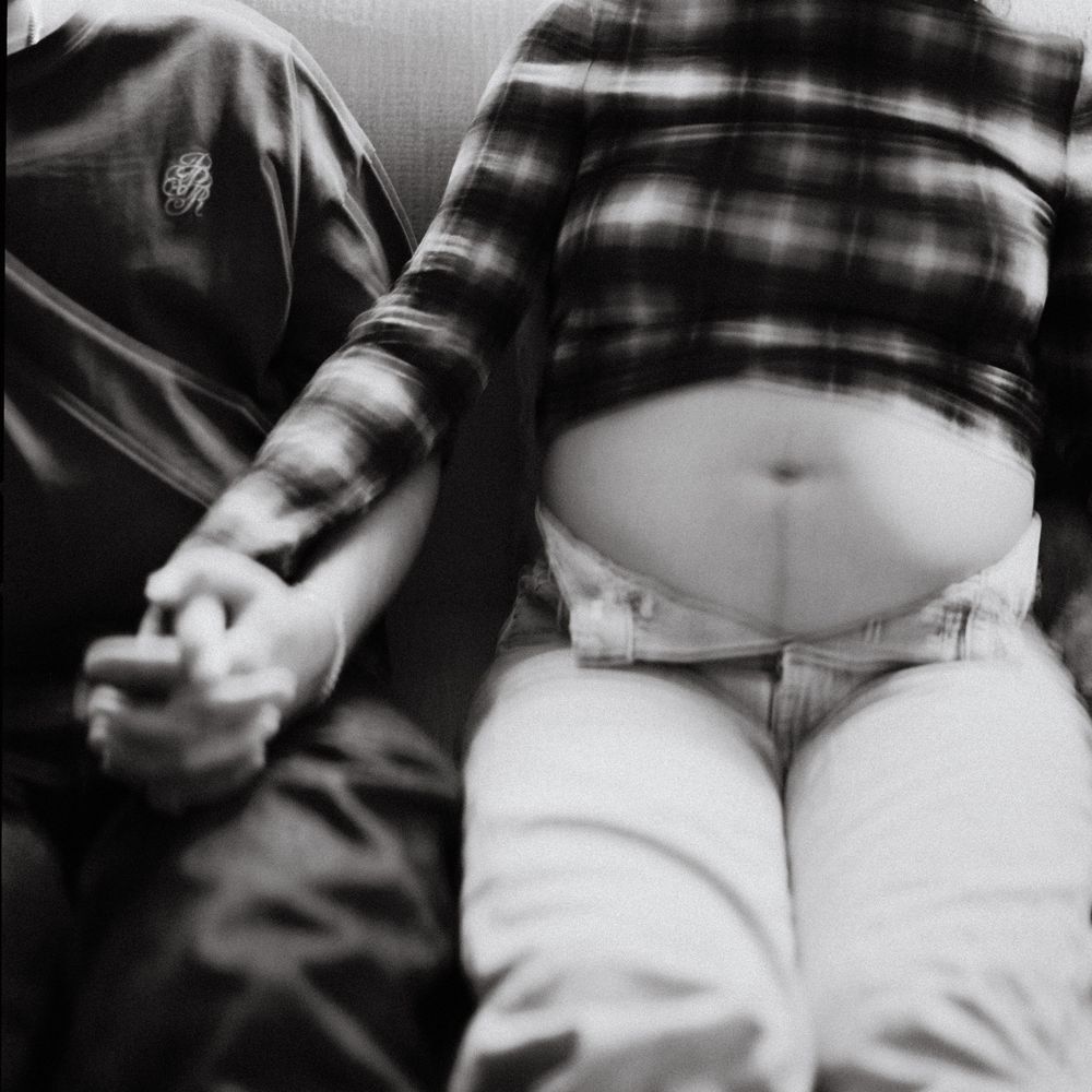120mm black & white close up of the mother to be and her belly while holding hands with her love in their hotel in Kennebunkport, Maine.