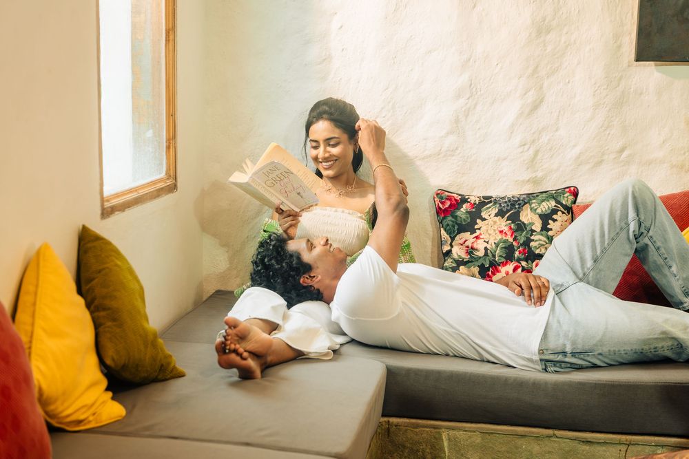 Person relaxing on a white couch with a yellow throw pillow while using a mobile device.