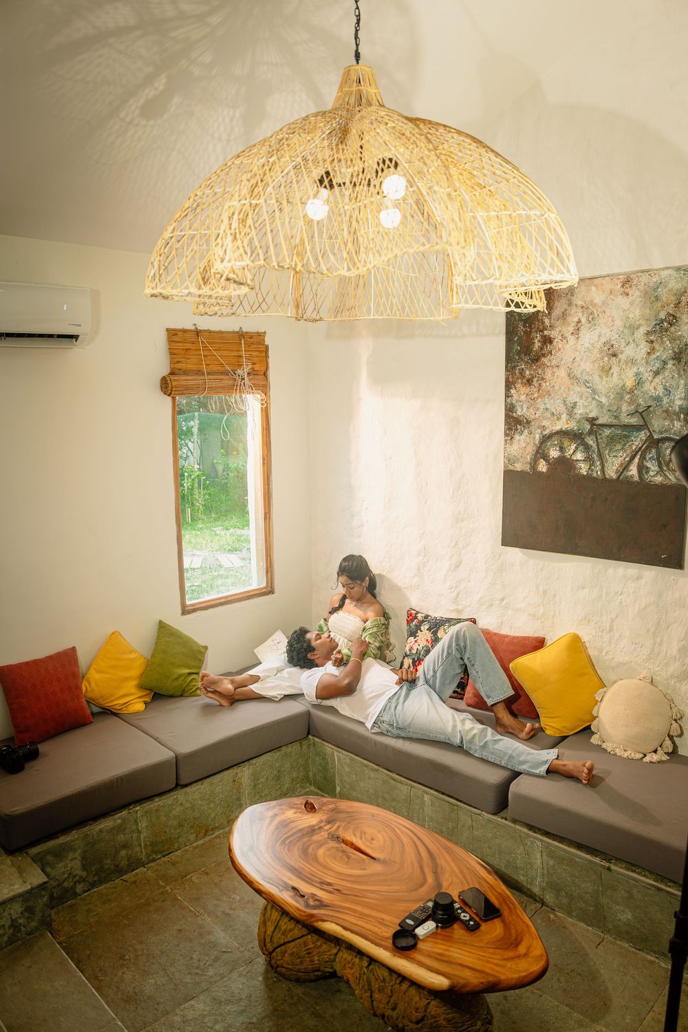 Cozy lounge area with built-in seating, colorful throw pillows, and woven pendant lamp creating a warm atmosphere.
