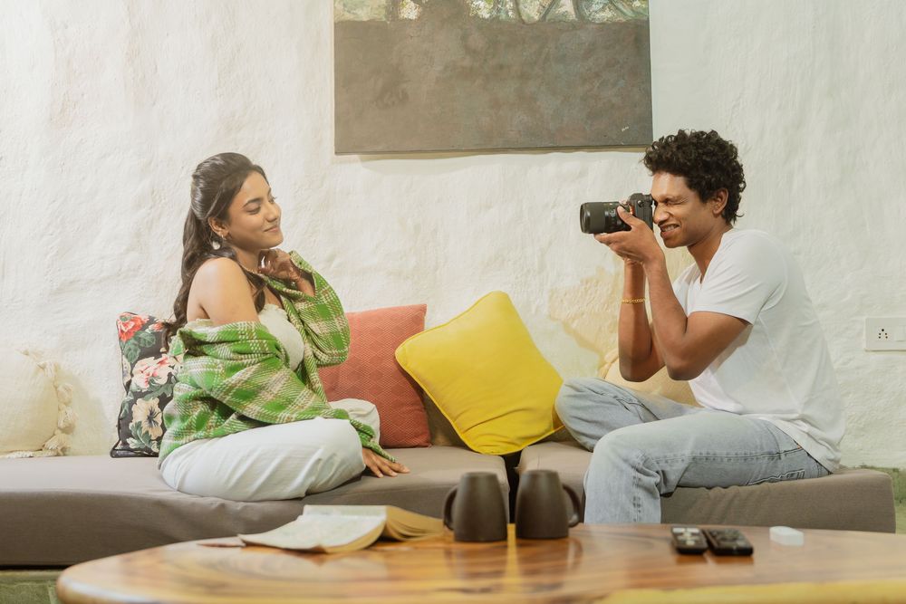 Couple relaxing together on couch with camera and laptop while enjoying leisure time at home.