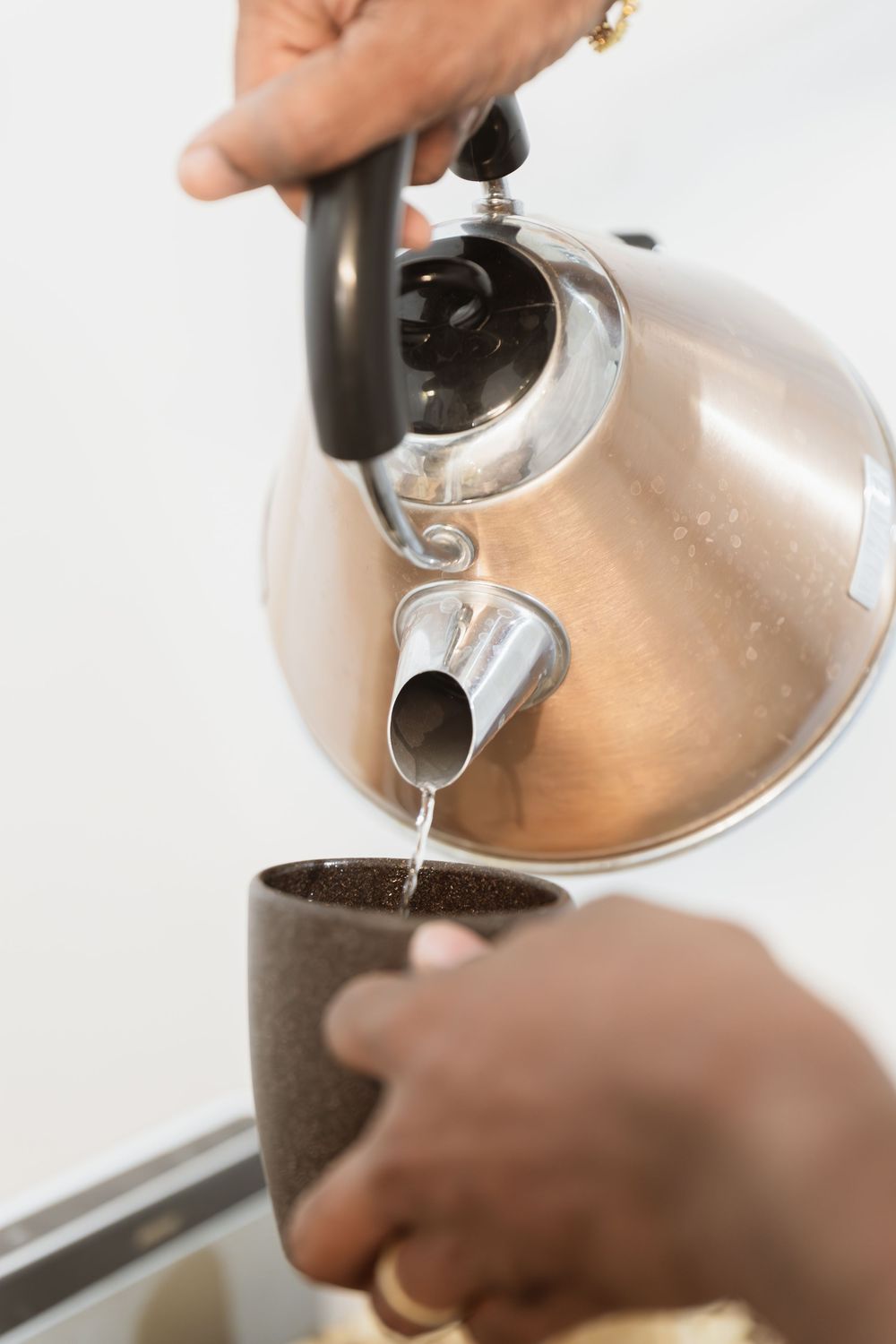 Coffee being poured from a silver kettle into a filter in soft lighting.