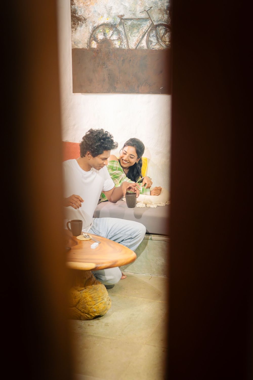 A couple shares an intimate moment while drinking coffee and laughing together.