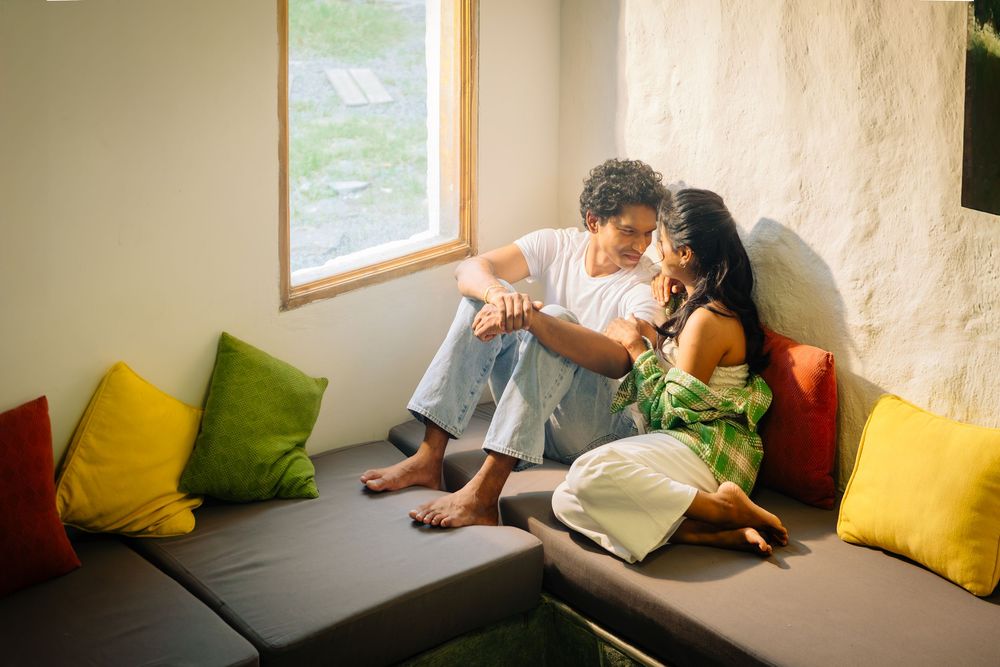 Movement sequence showing relaxed poses on a couch with colorful yellow and green throw pillows by a window.