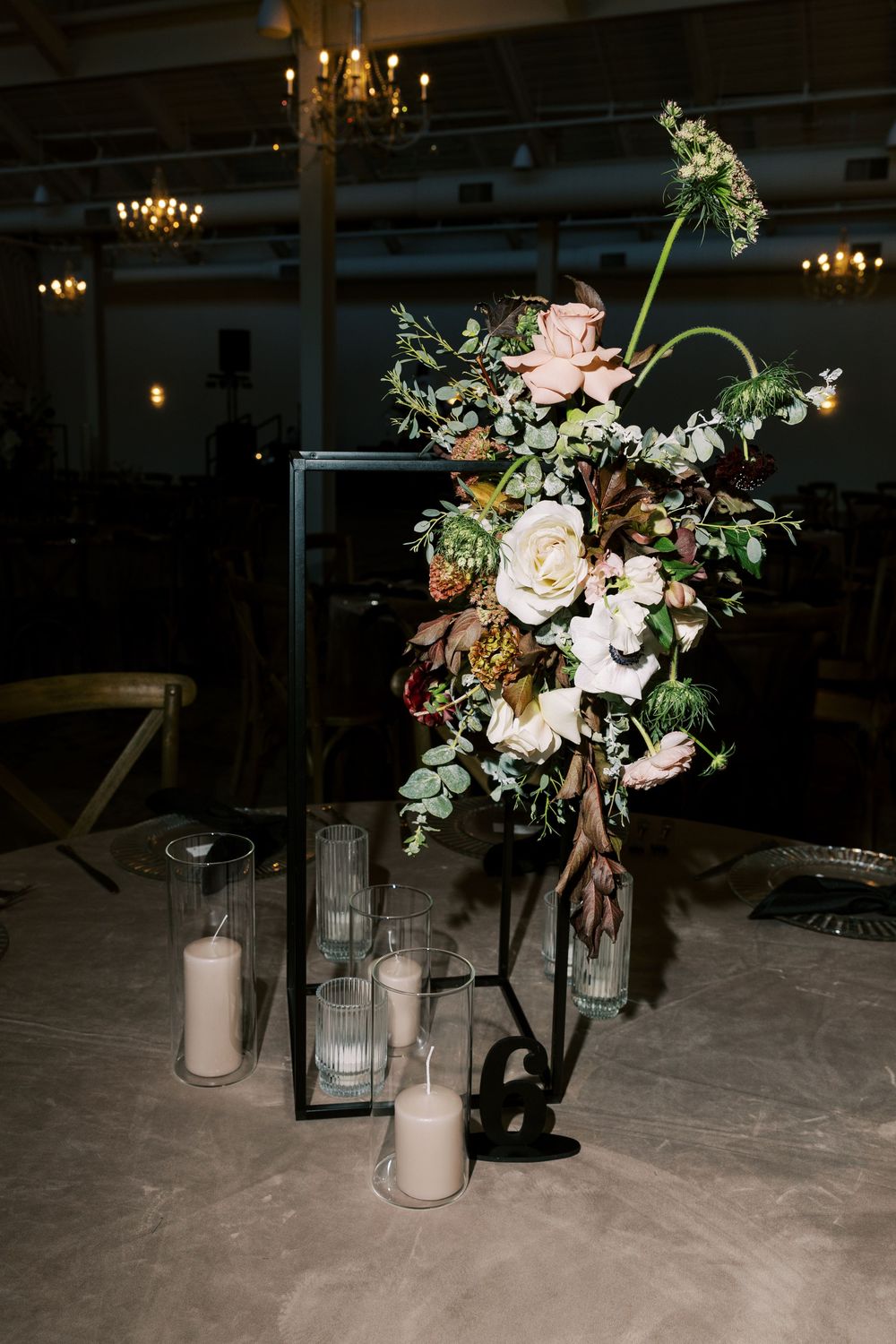 Romantic wedding centerpiece with roses and mixed flowers in black lantern stand with pillar candles.