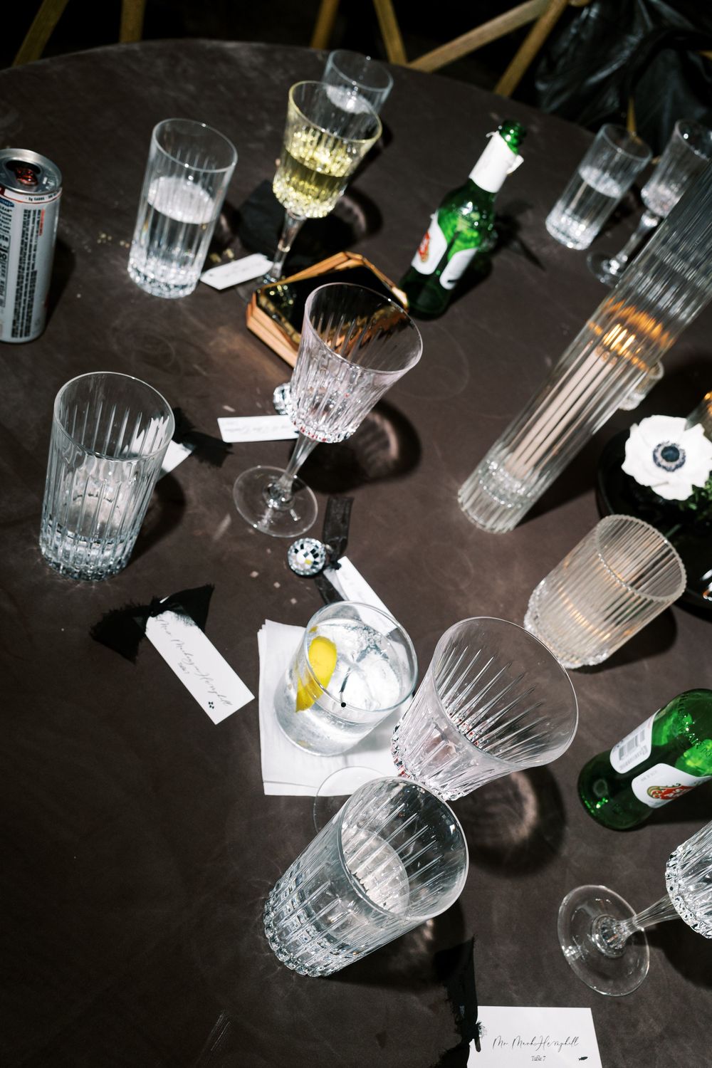 Crystal glassware and drink glasses scattered on a dark surface creating reflective patterns.