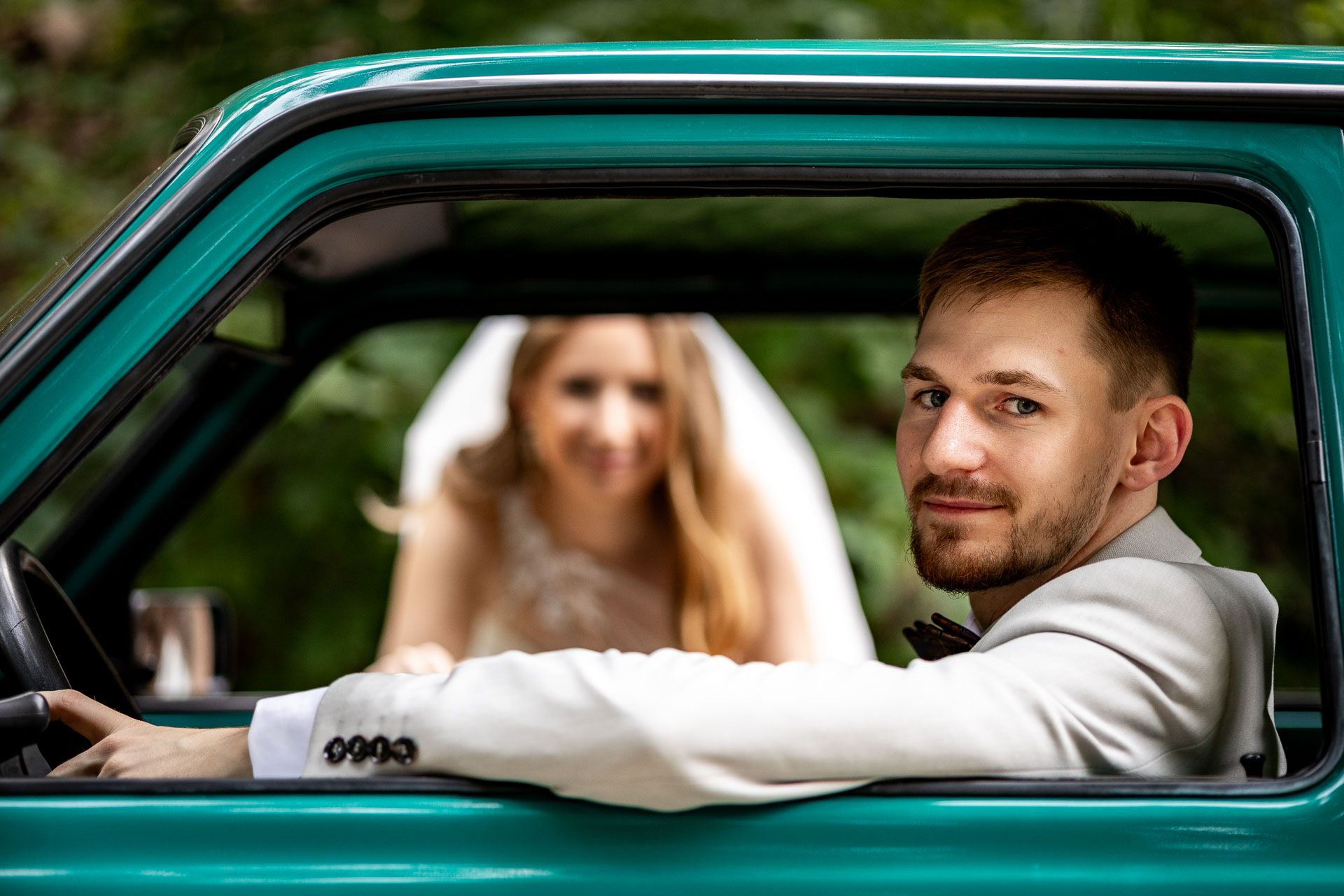 Close-up shots of newlyweds in a vintage teal car.