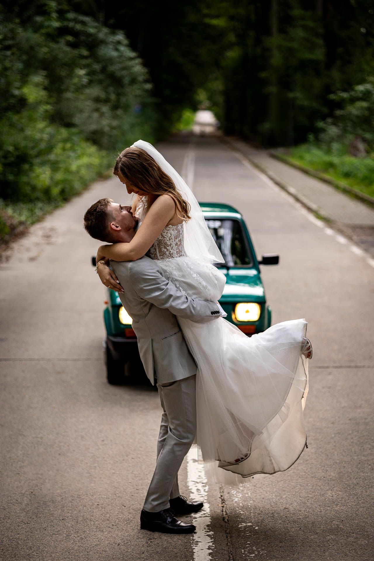 Dramatic wedding dance dip pose with teal vintage car in background.