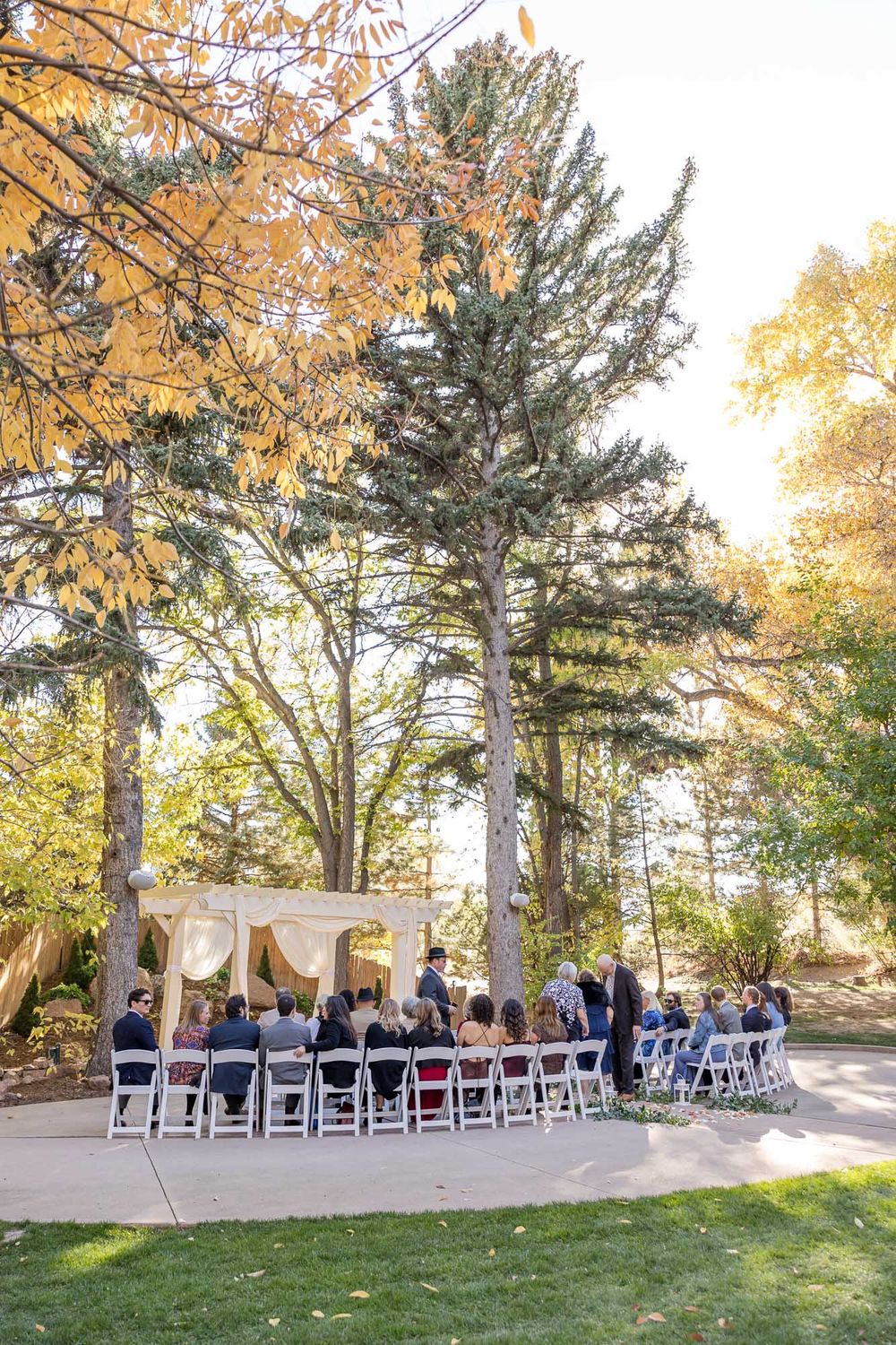 Rows of white chairs set up for an outdoor autumn wedding ceremony under golden trees.
