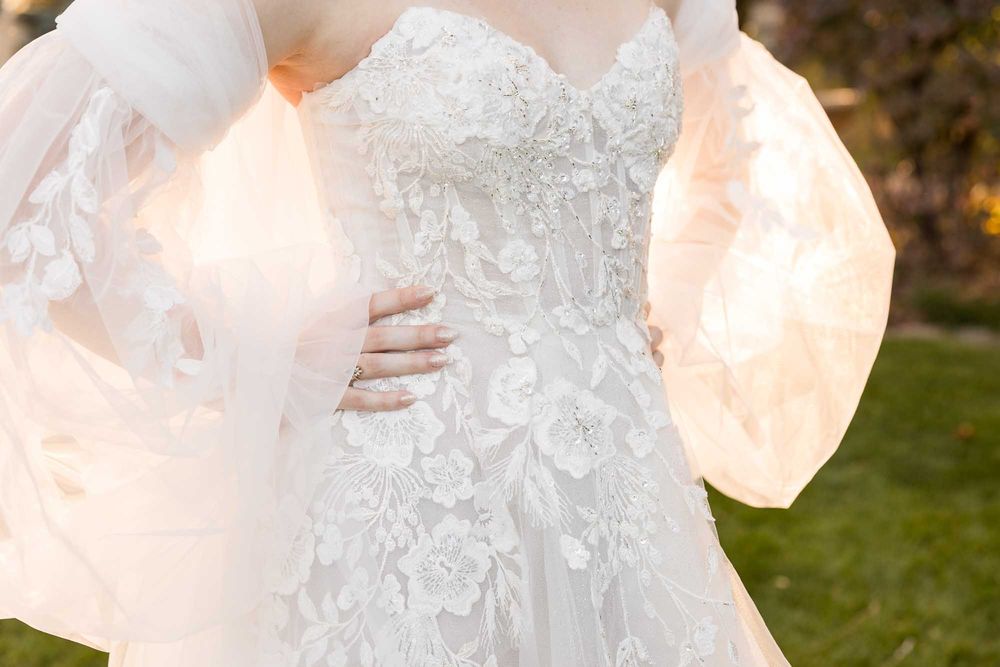 Close-up details of an intricate white lace wedding dress with delicate embellishments.