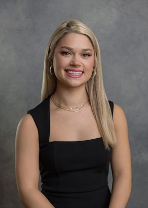 Professional studio portrait of person in black sleeveless top against gray background.