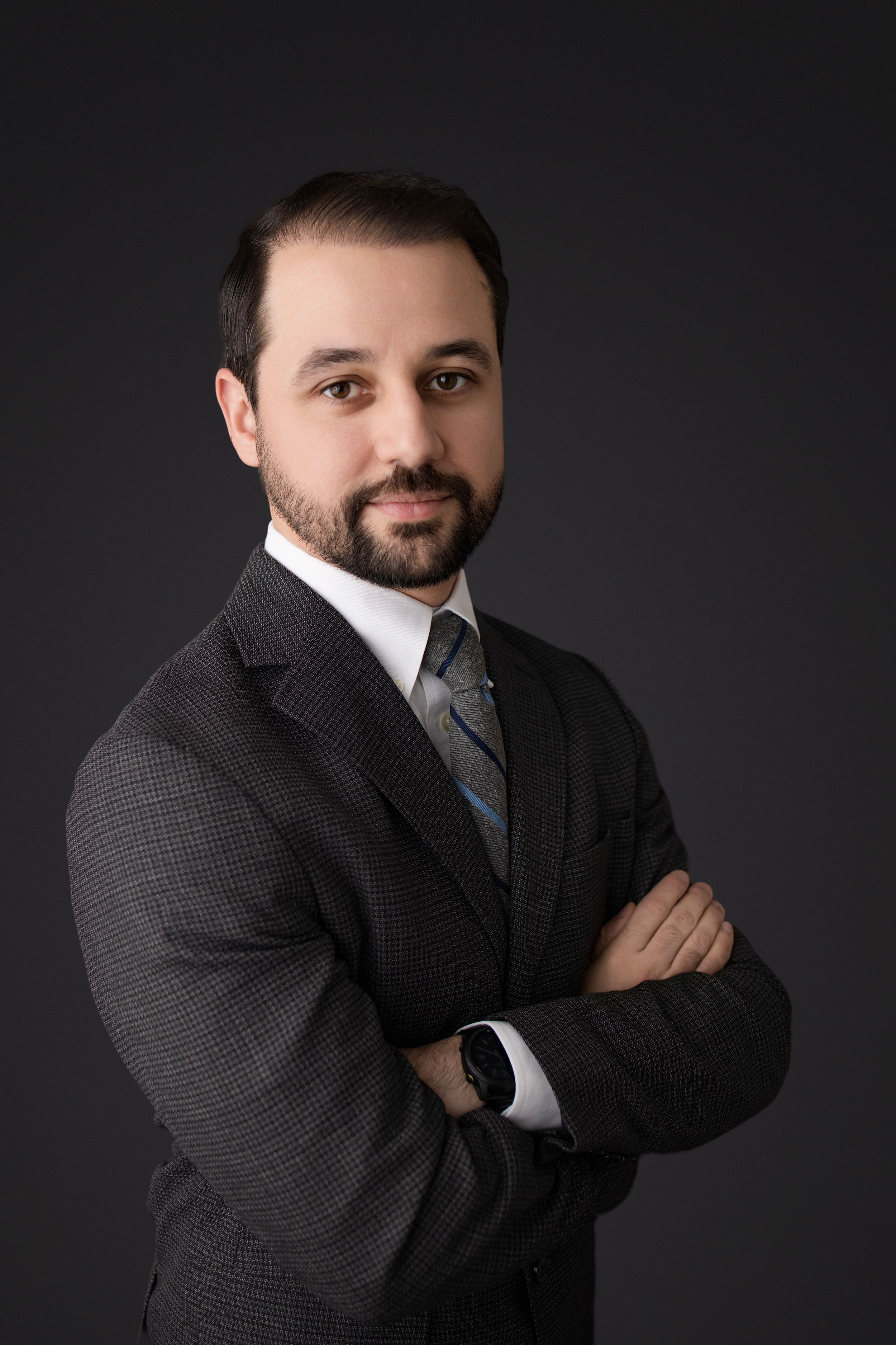 Professional studio portraits of a person in a dark suit against black background showing different poses and expressions.