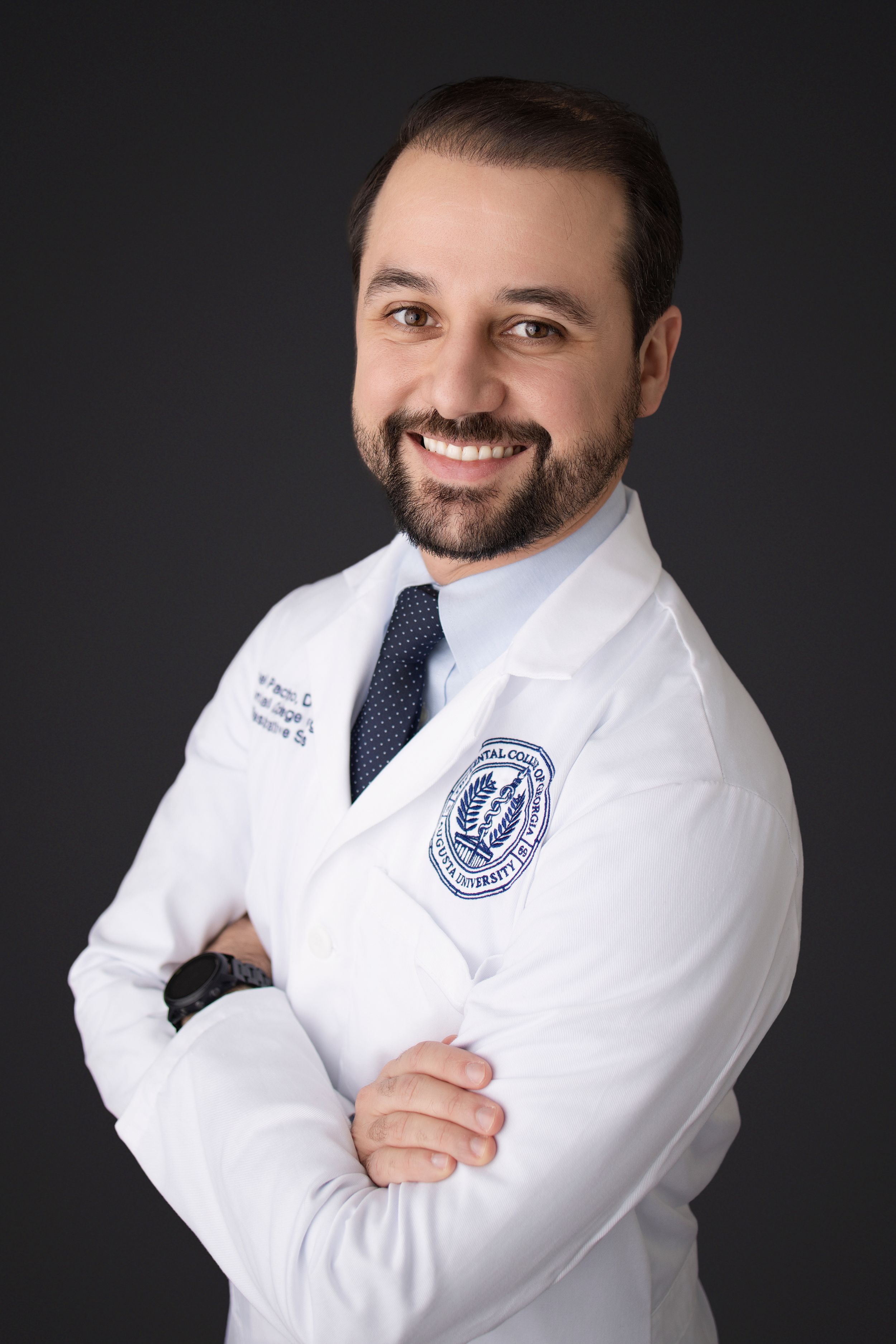 Professional wearing white medical coat and navy tie poses against dark background in studio portraits.