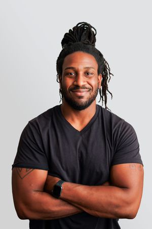 Person wearing black t-shirt smiling with arms crossed in multiple poses against white background.