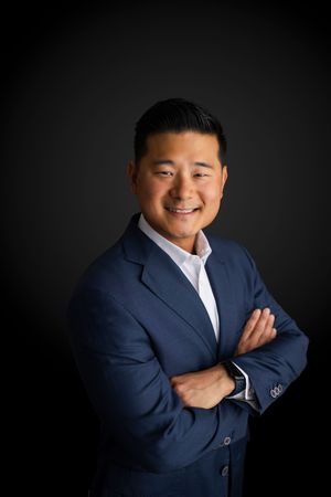A person in a navy blue blazer poses against a dark background in a series of expressive portrait shots.