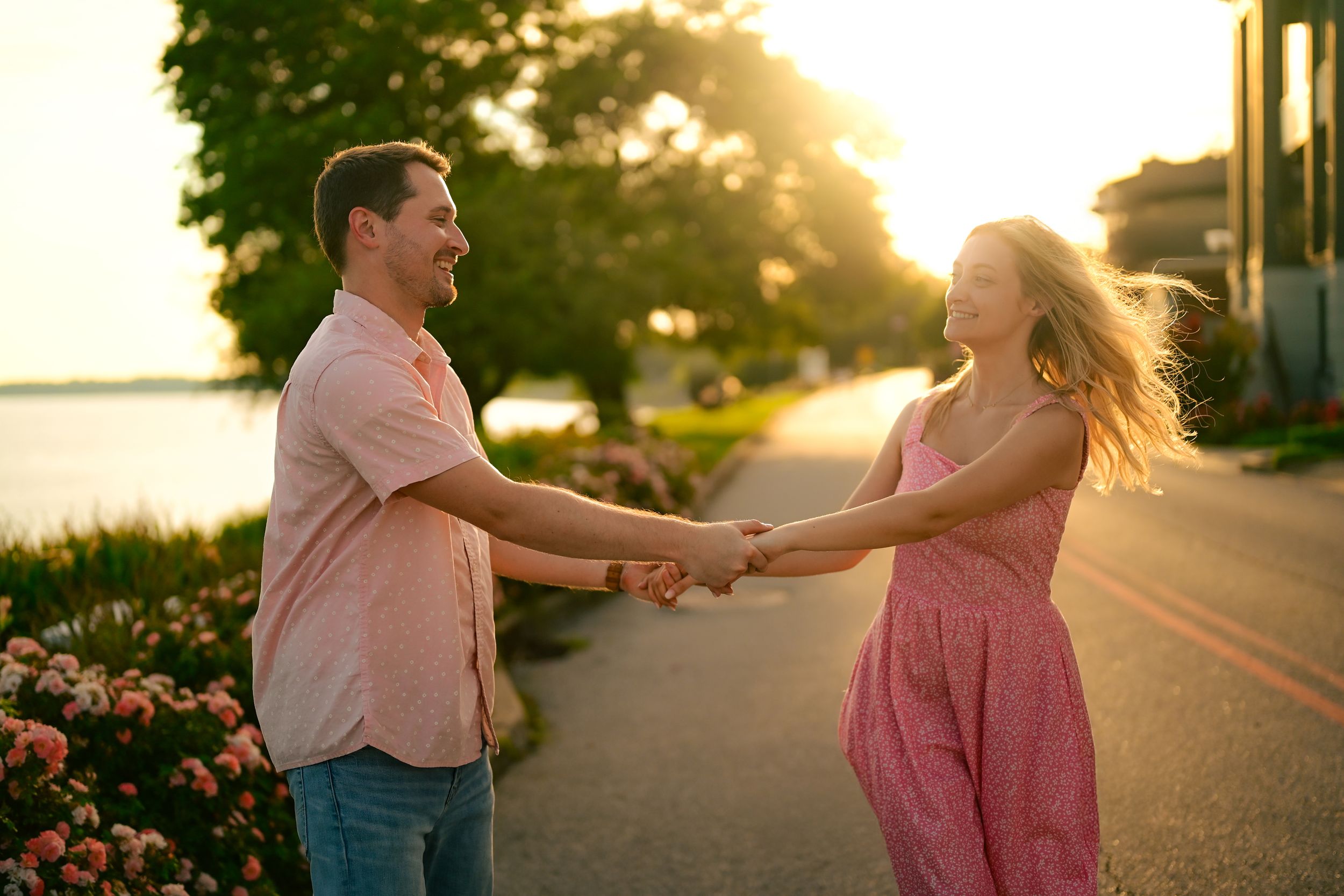 A couple dances together during golden hour on a path lined with pink roses.