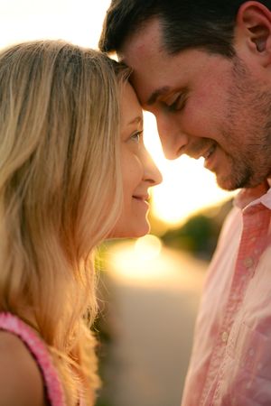 Romantic couple sharing an intimate moment at sunset with golden light illuminating their profiles.