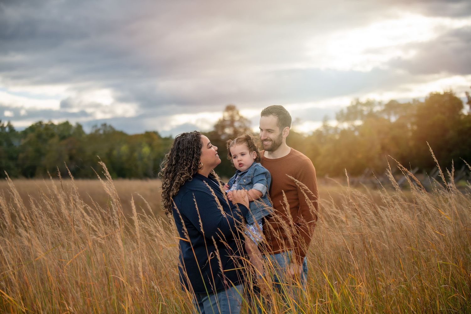 Family sharing joyful moment together in golden field during sunset.
