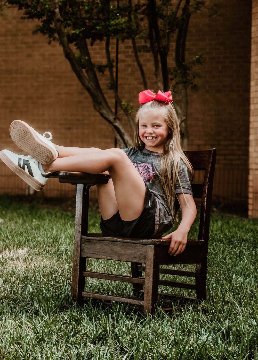 Back to school themed photo setup with wooden chair against brick wall.