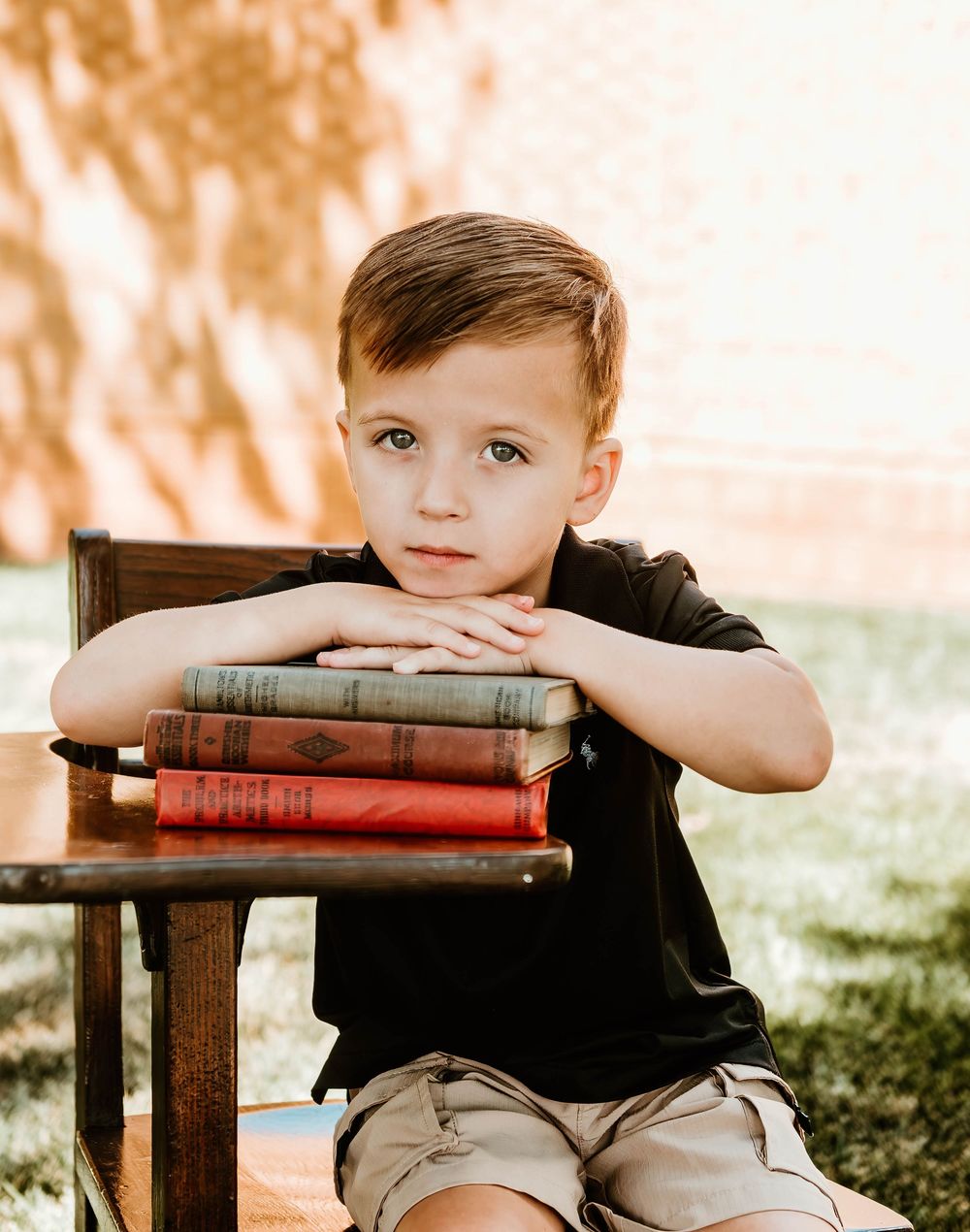 Vintage books stacked on a wooden chair in a garden setting with natural lighting.