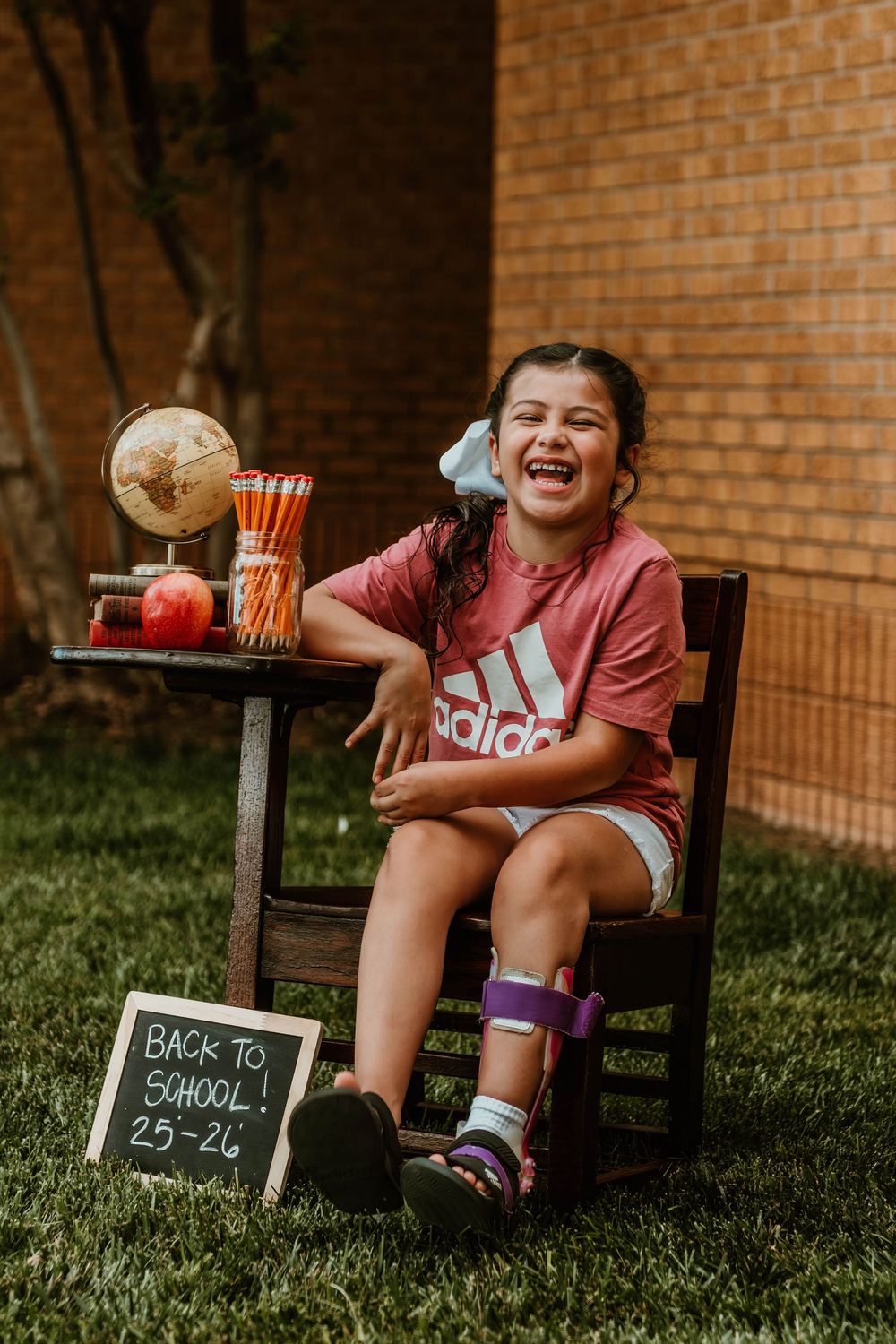 Cheerful back-to-school scene with books and props against brick wall backdrop.