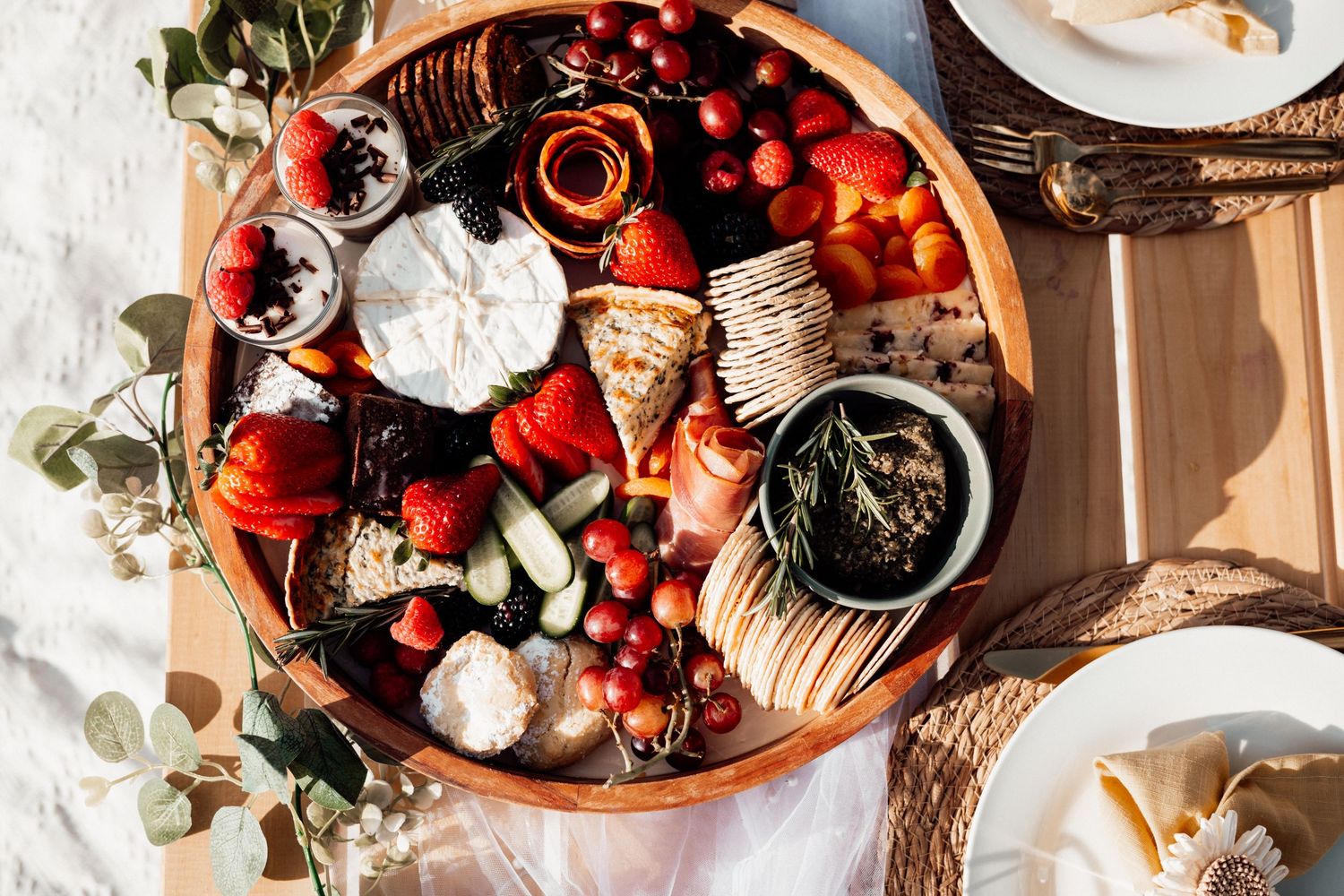 Overhead view of a rustic table setting with fresh berries, pastries, and coffee in warm morning light.