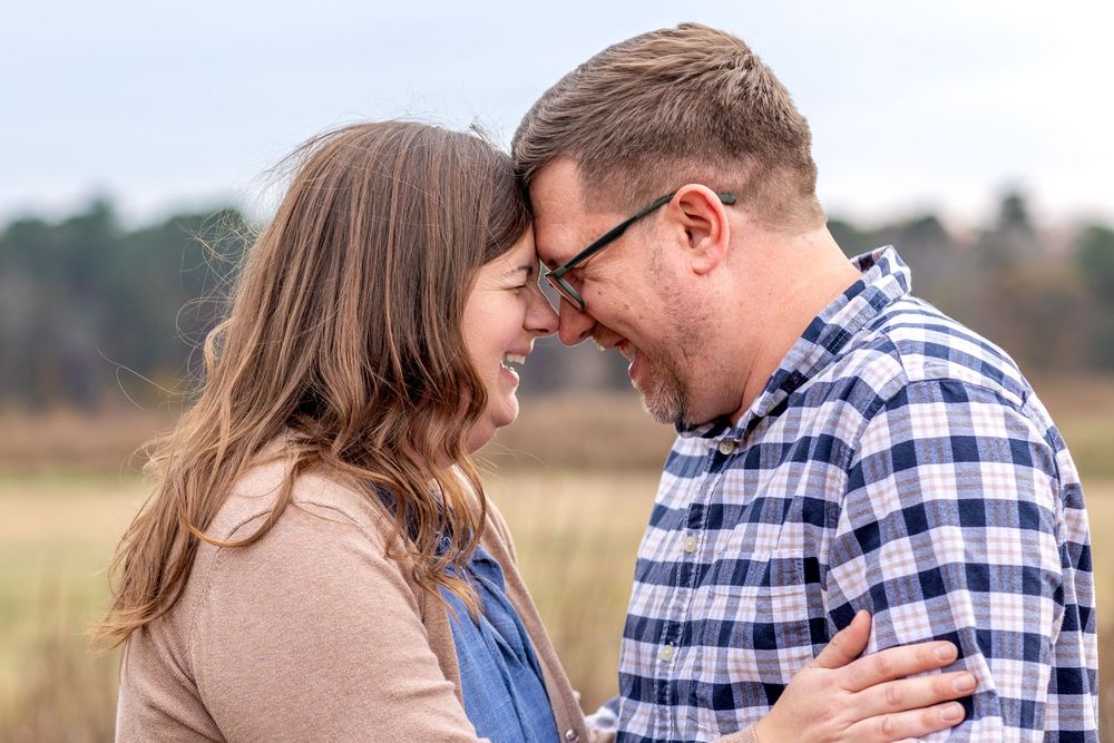 A couple in plaid and denim share romantic moments in a golden field at sunset.