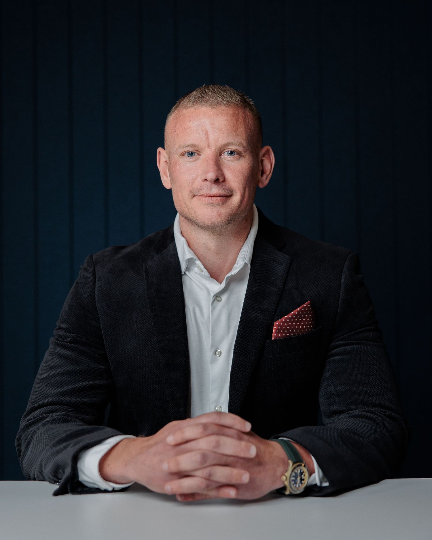Professional headshot series showing person in dark suit and white shirt against blue background.