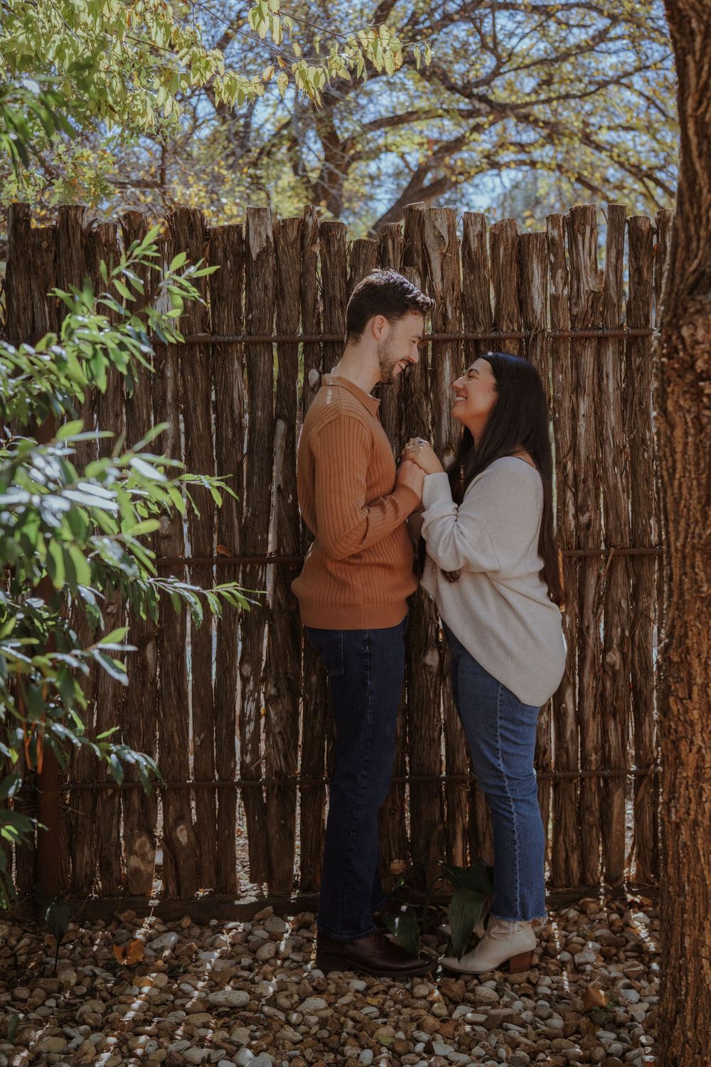 A couple shares intimate moments against a rustic wooden fence backdrop in a series of romantic outdoor photos.