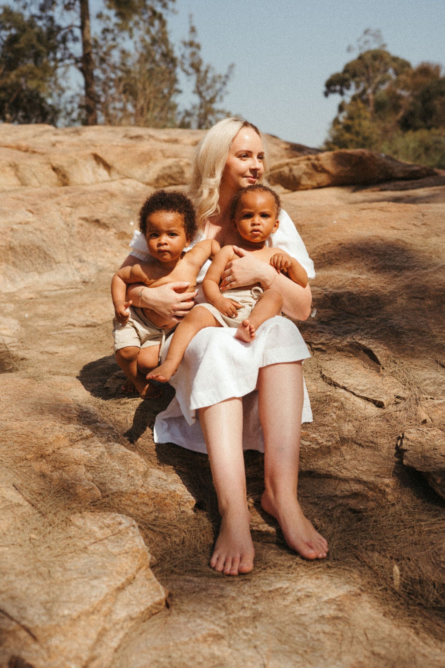 People sitting on rocky terrain wearing white clothing in warm sunlight.