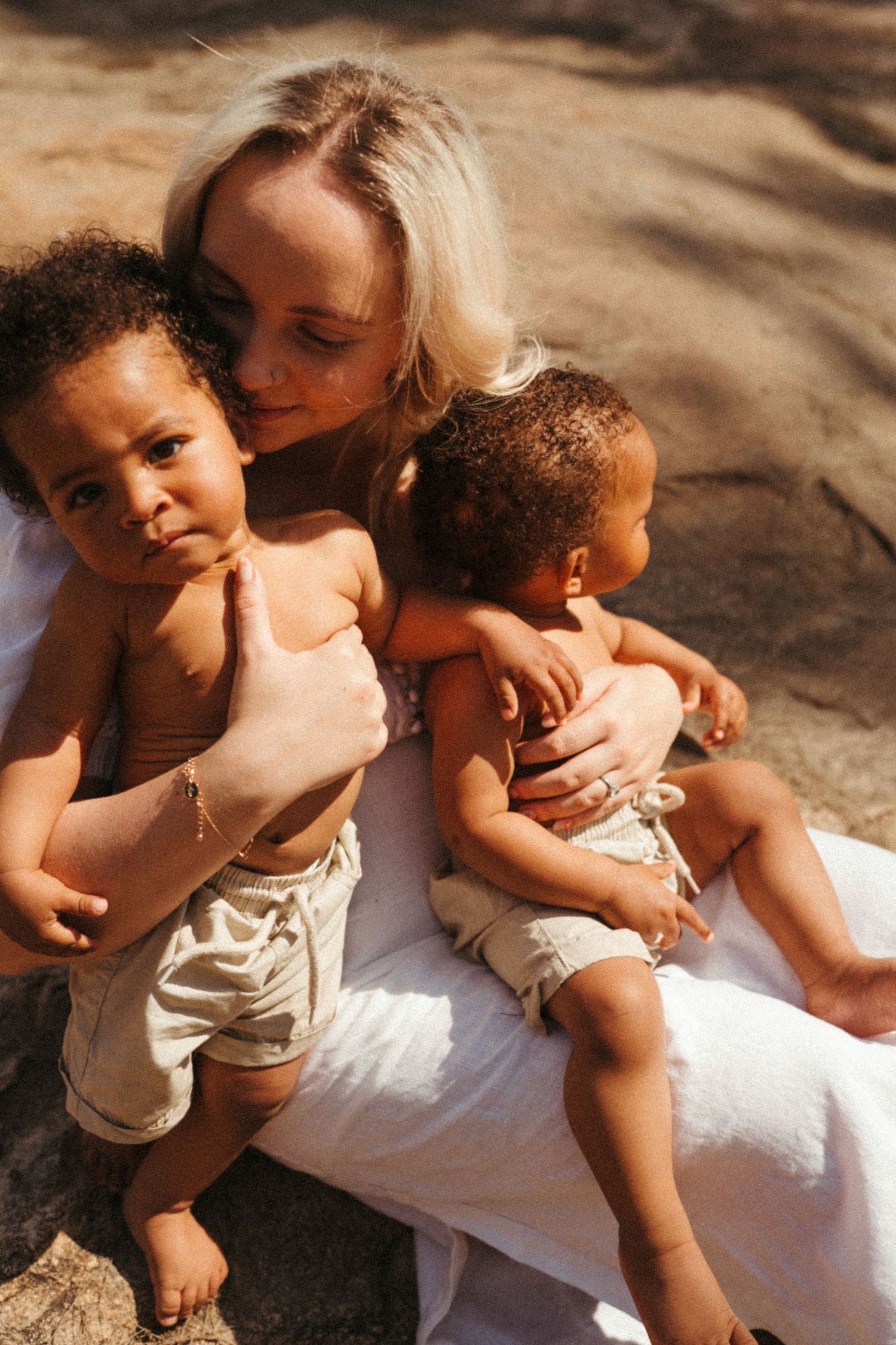 A tender outdoor photoshoot showing gentle embraces and intimate moments on a natural rock surface.