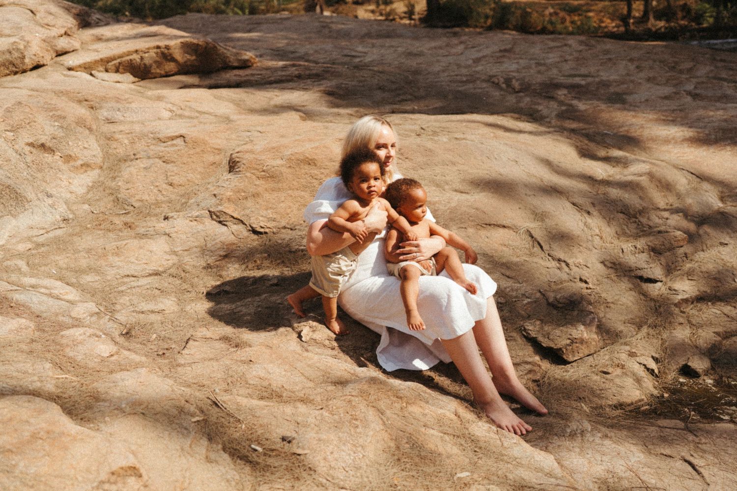 Natural light photography series showing tender moments on a textured stone surface.