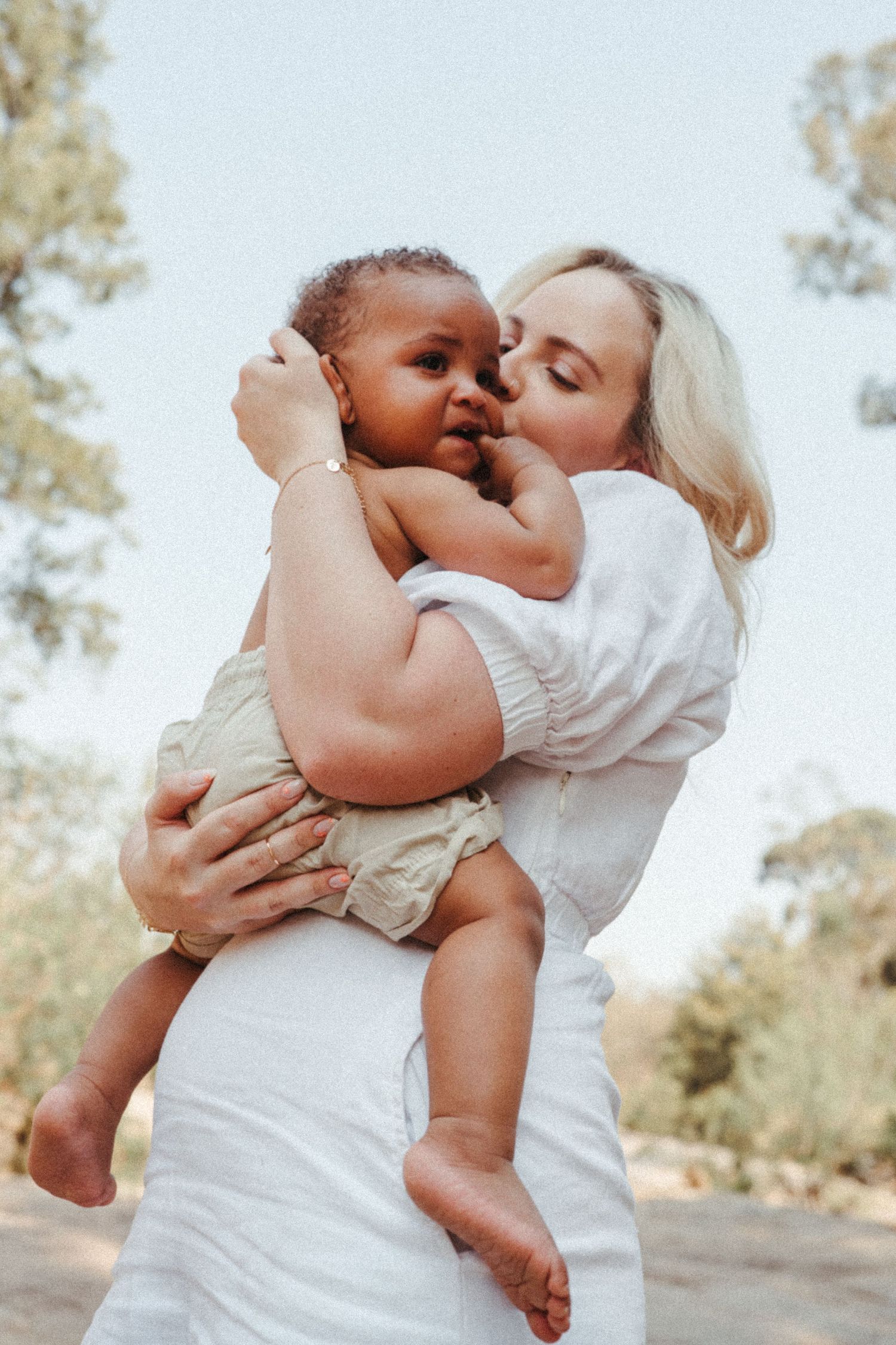 Sunlit outdoor portrait series showing affectionate moments against a natural backdrop.