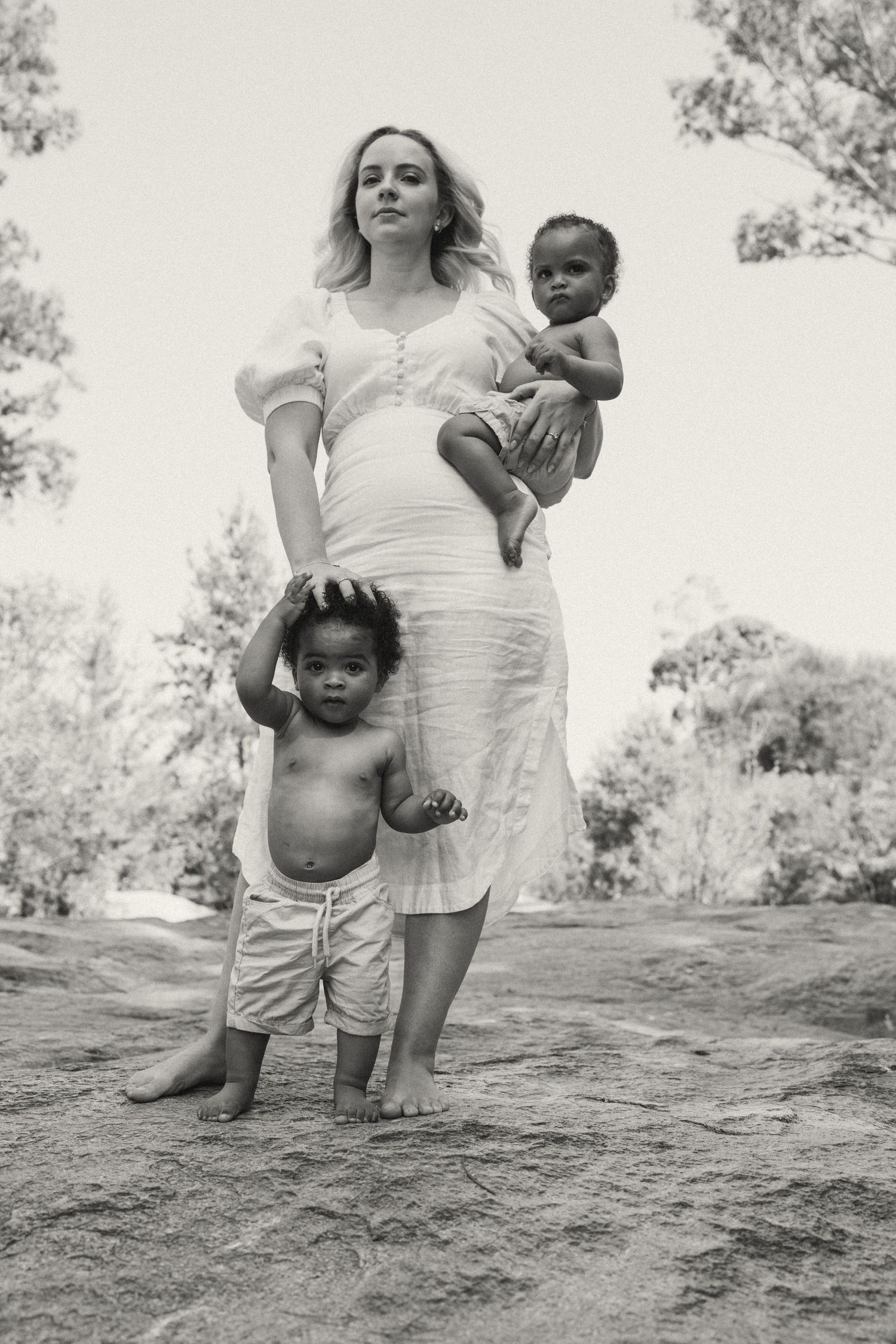 A tender outdoor photoshoot showing affectionate moments between parent and child on rocky terrain.